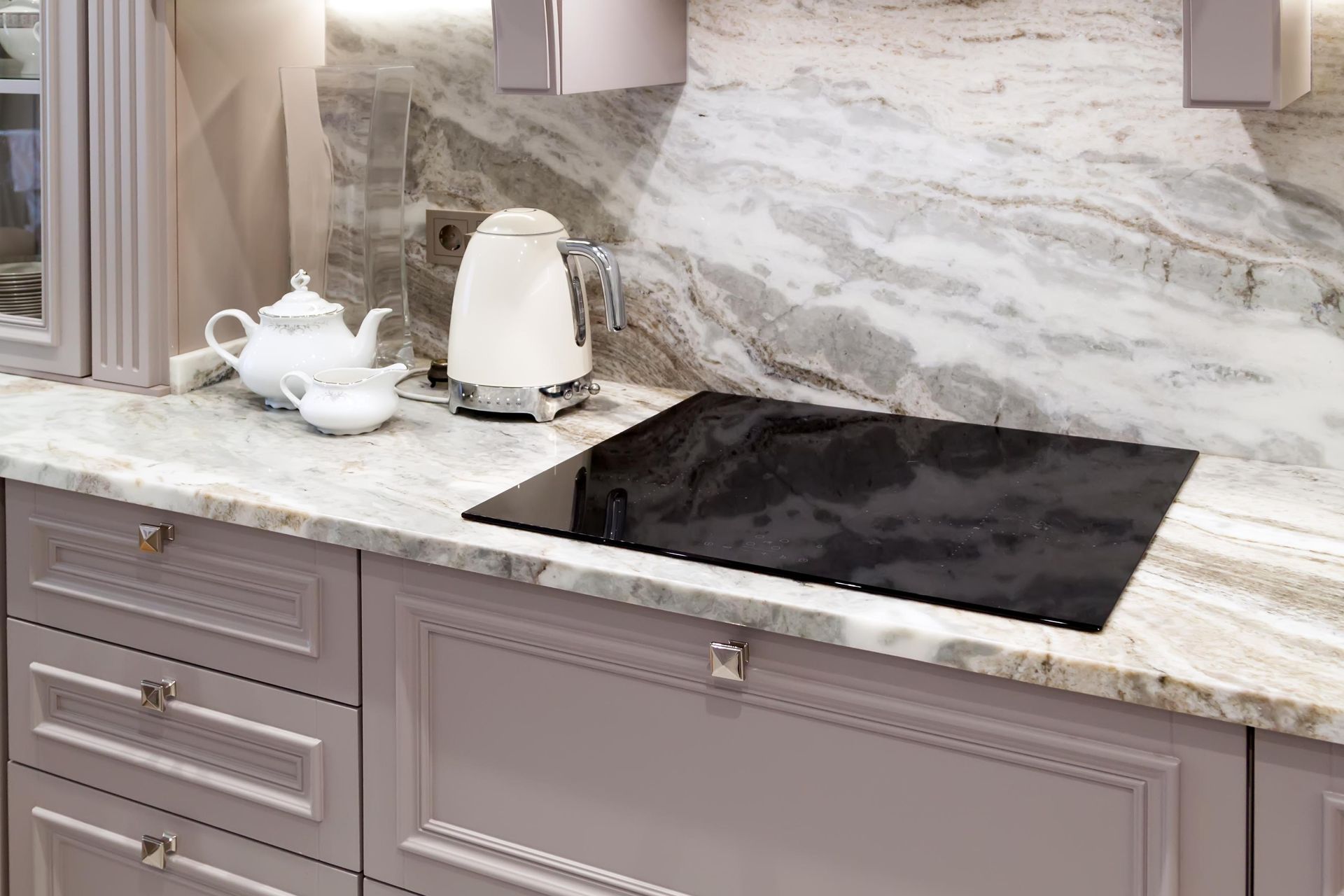 A kitchen with a stove top oven, a kettle, and a teapot on the counter.