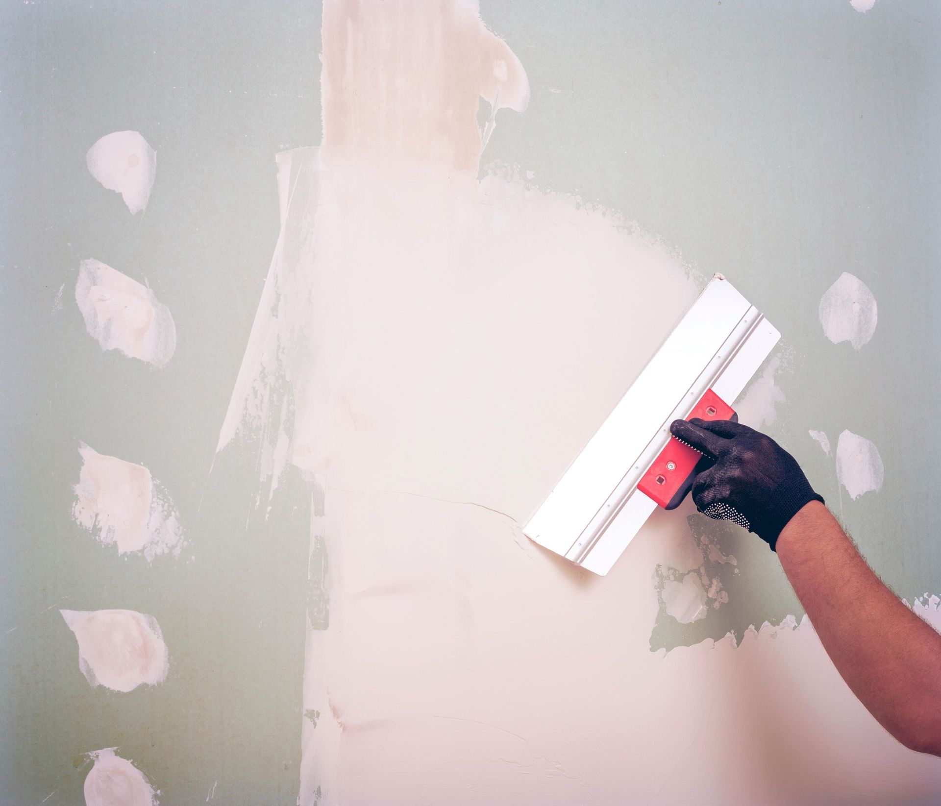 A person is plastering a wall with a spatula.