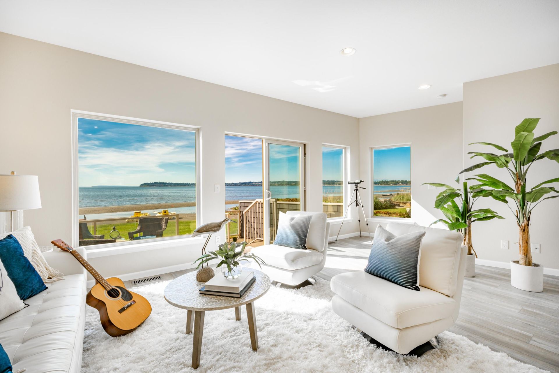 A living room with a guitar on the table and a view of the ocean.