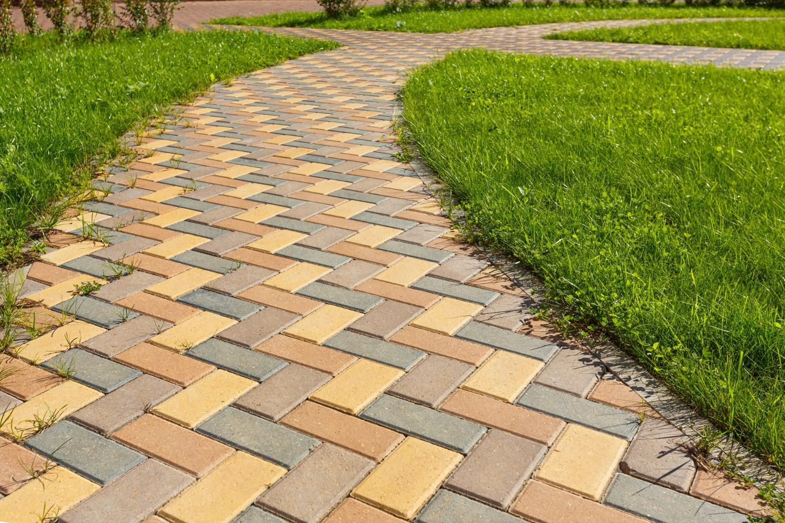 A brick walkway going through a lush green field.