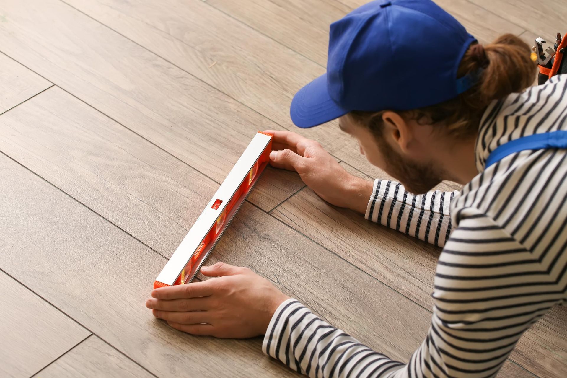 A man is laying on the floor using a level.