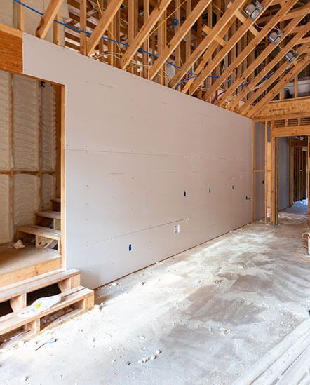 An empty room in a house under construction with a large wall.