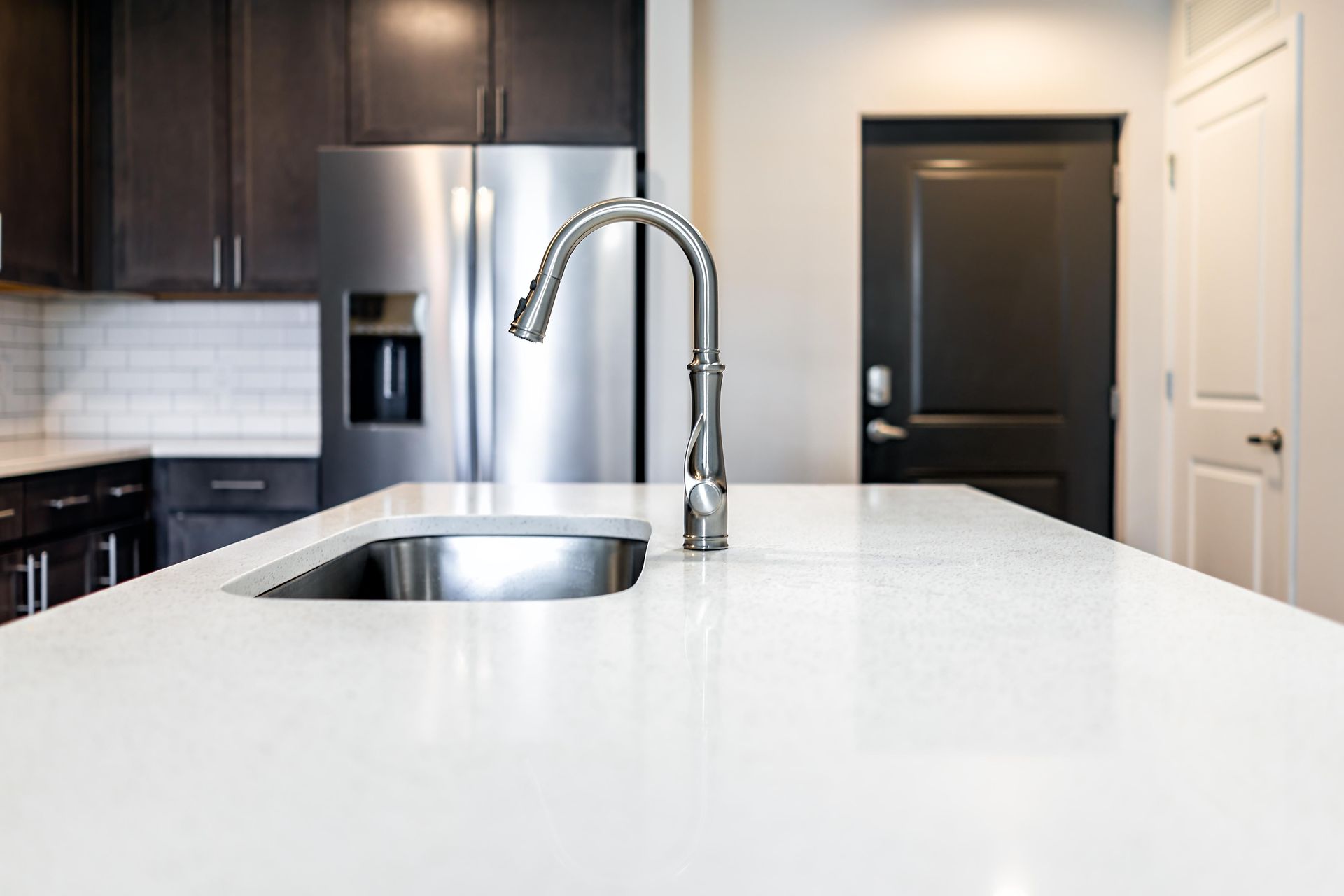 A kitchen with a sink, refrigerator, and faucet.