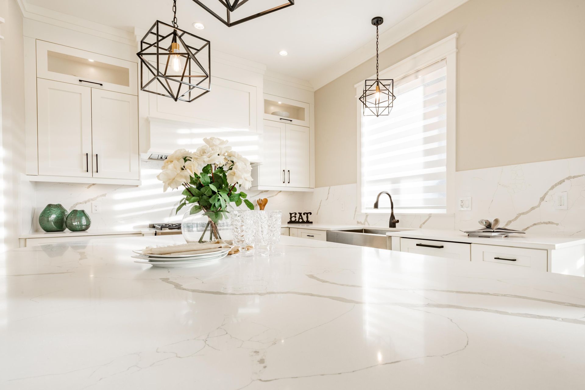 There is a vase of flowers on the counter in the kitchen.