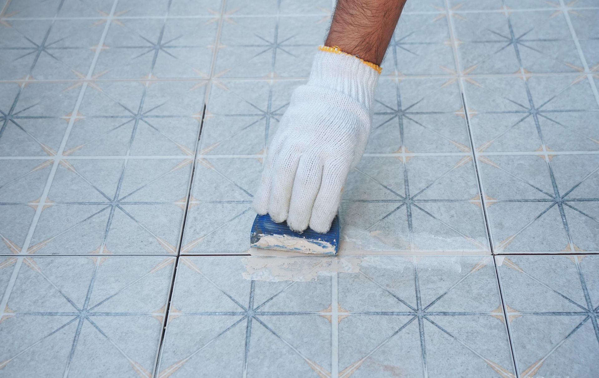 A person is cleaning a tile floor with a sponge.