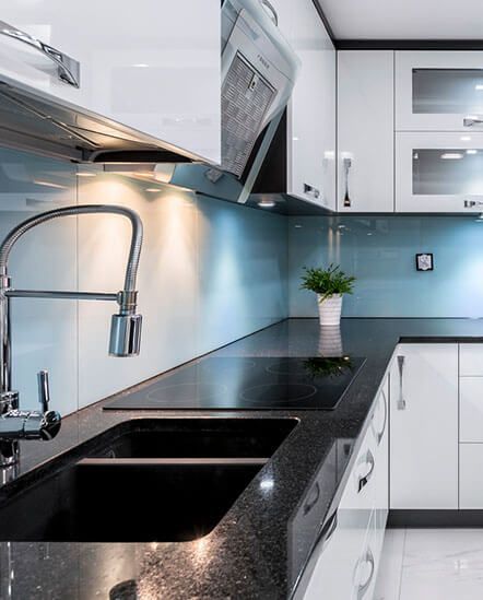 A kitchen with a sink, stove, and cabinets.