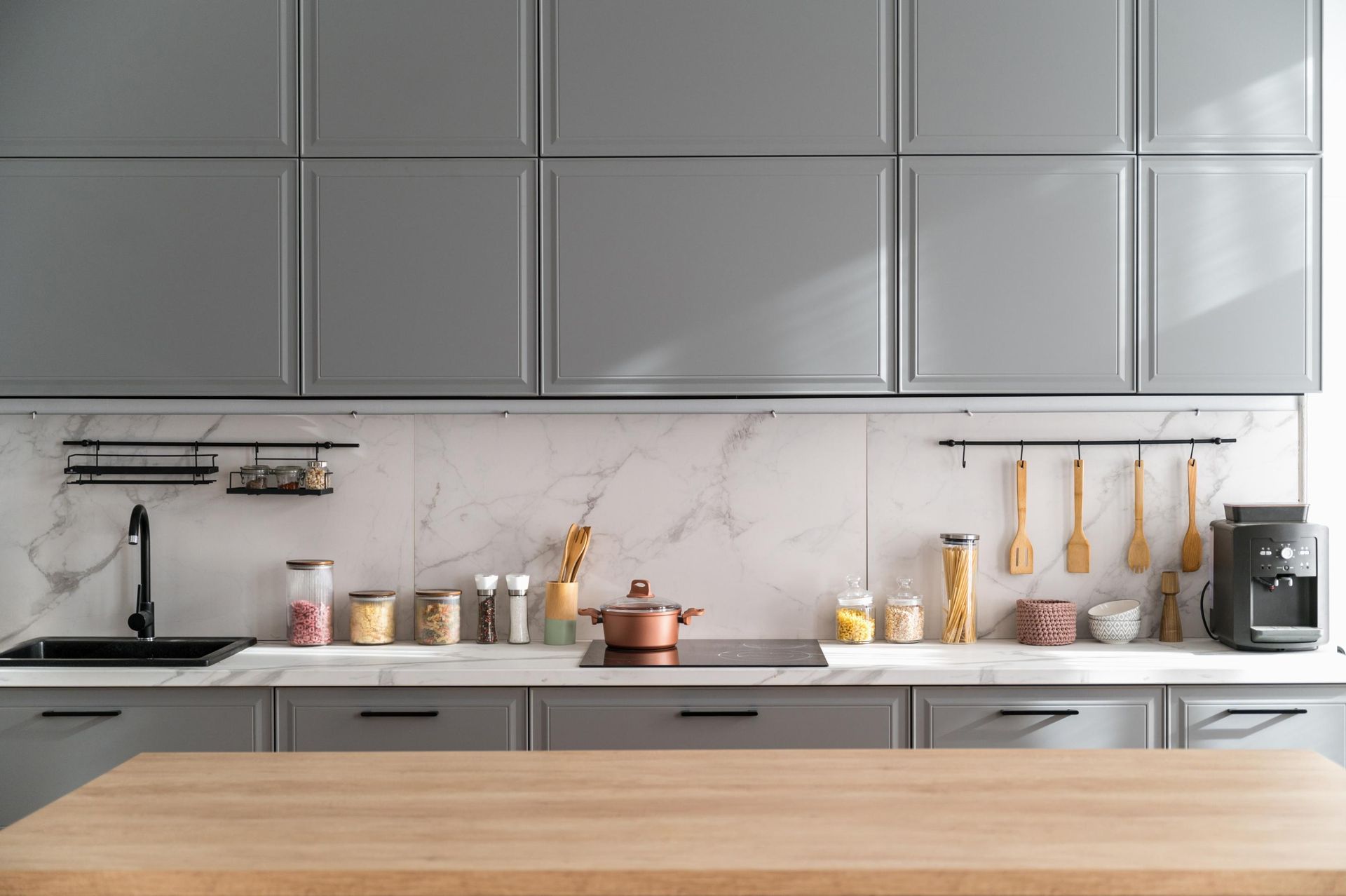 A kitchen with gray cabinets and a wooden counter top.