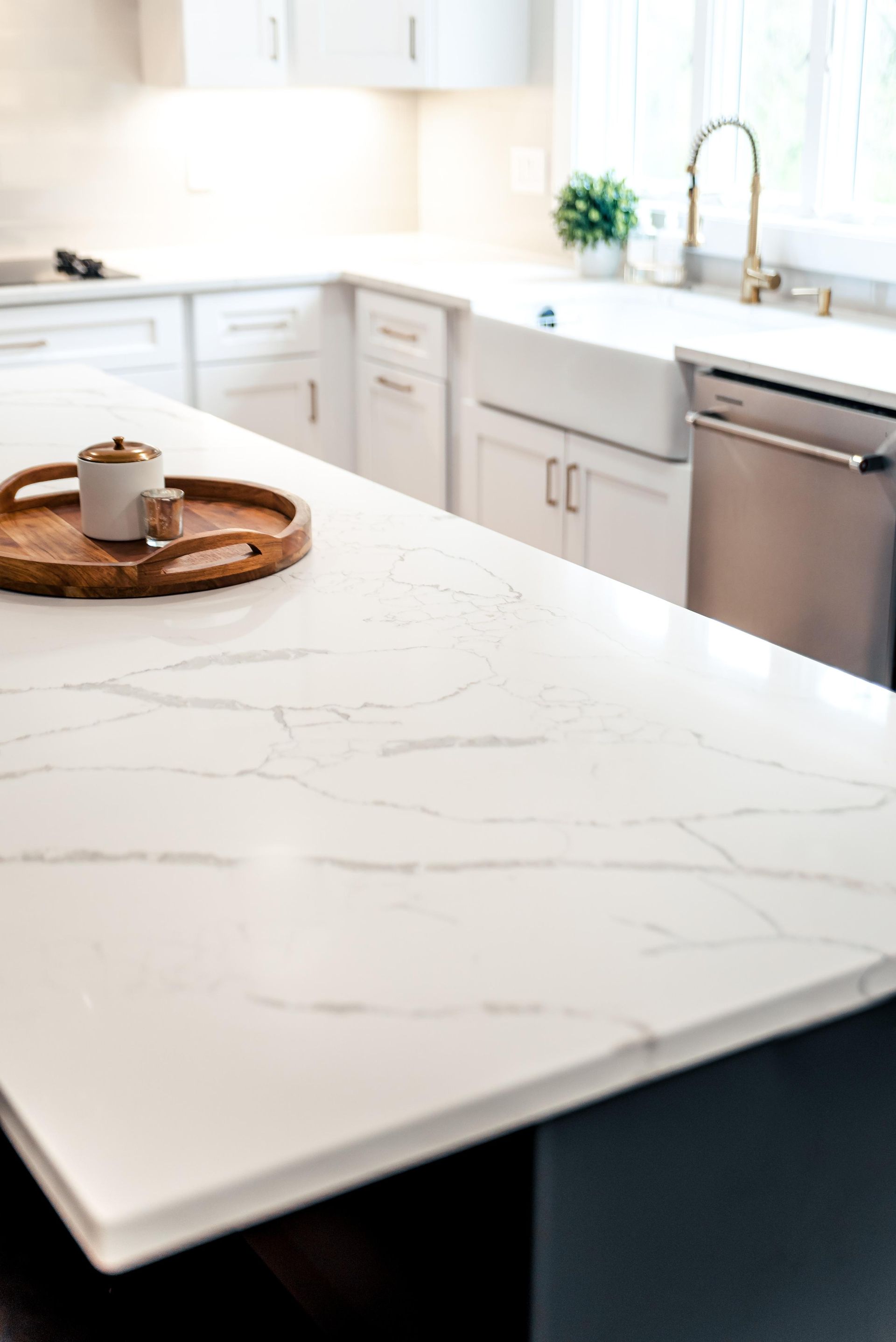 A white counter top in a kitchen with a wooden tray on it.