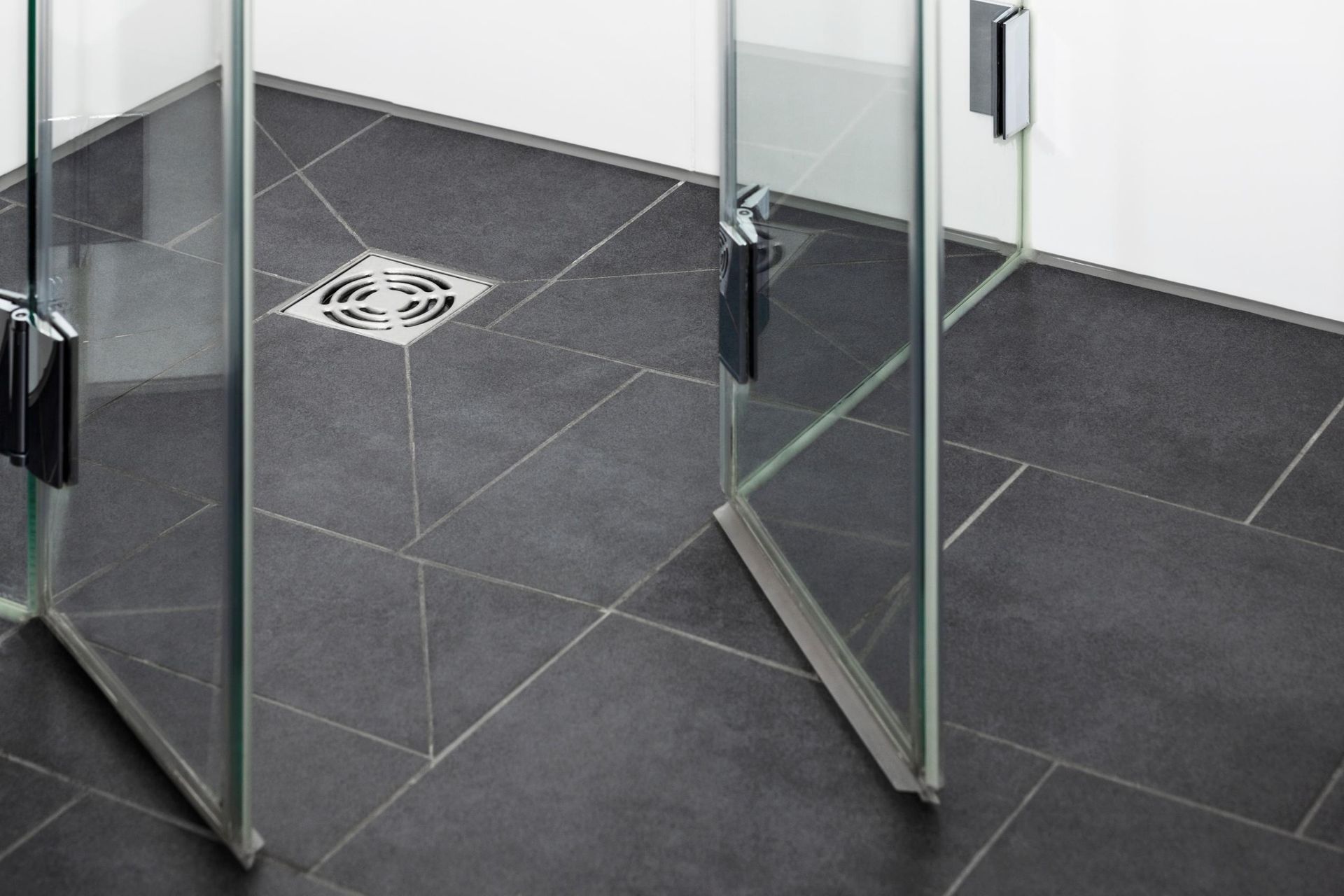 A bathroom with a black tile floor and a glass shower door.