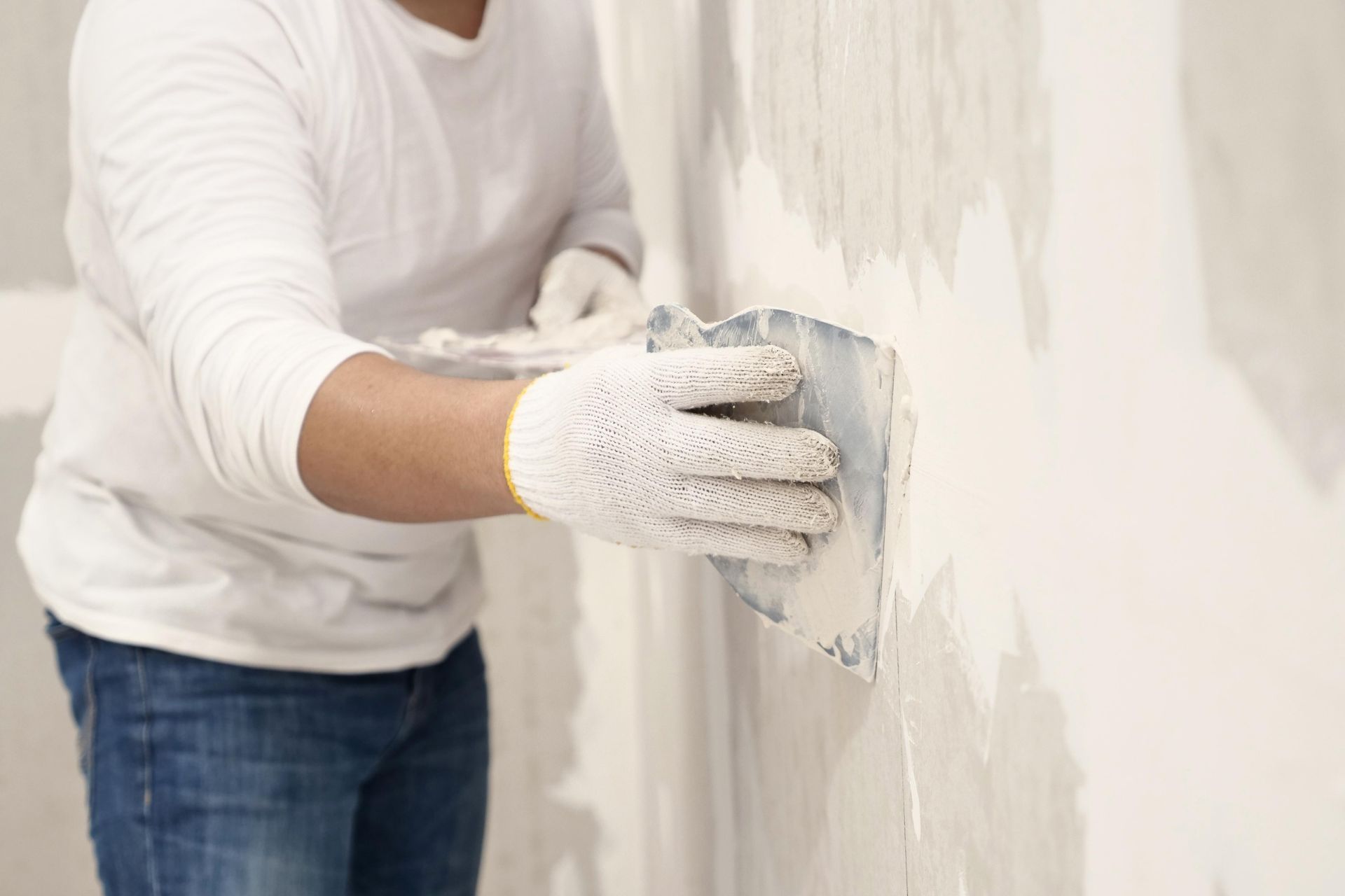 A man is plastering a wall with a trowel.