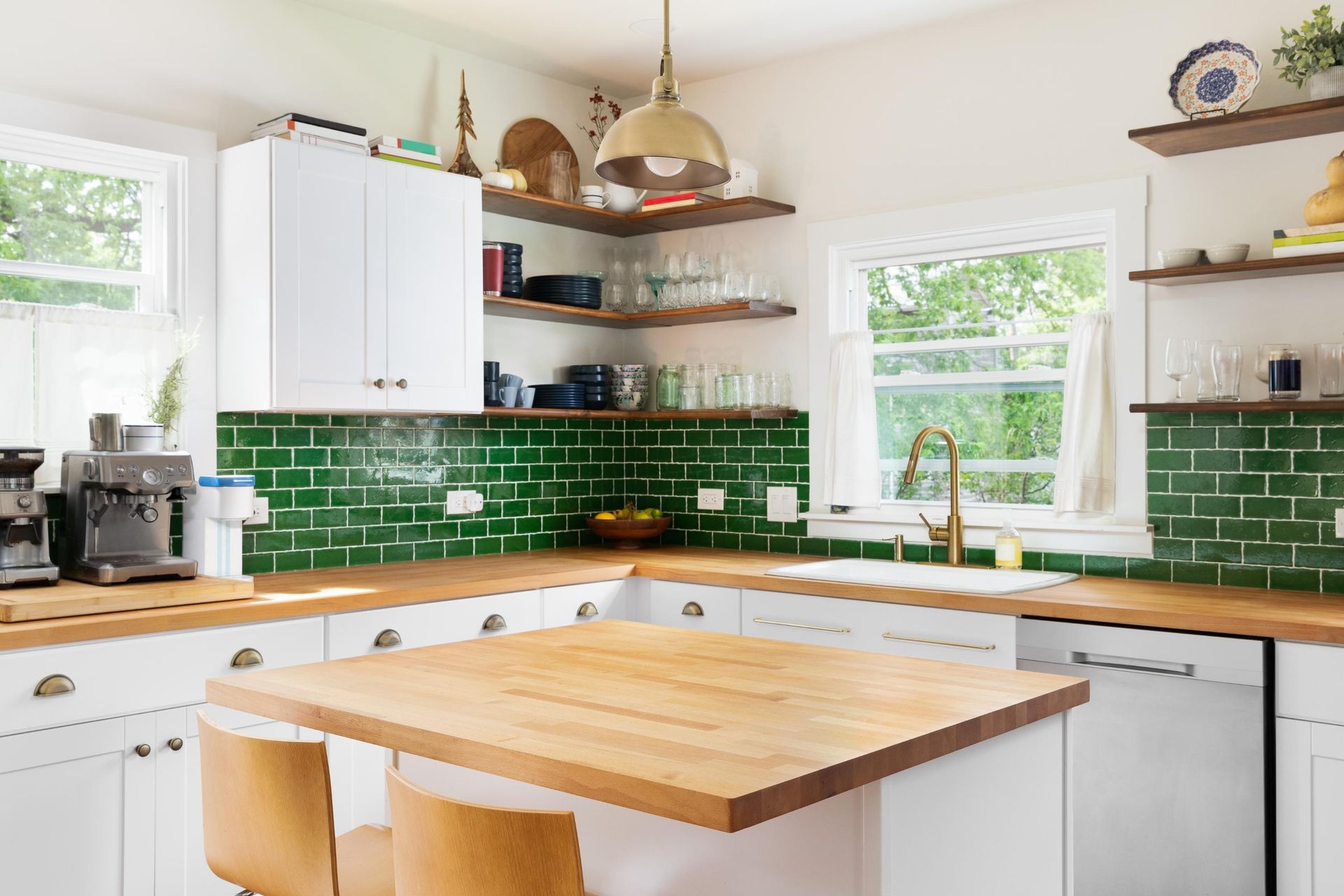 A kitchen with green tiles, white cabinets, wooden counter tops, and a wooden island.