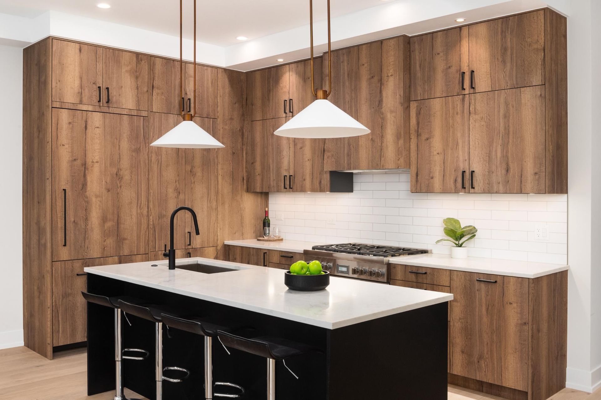 A kitchen with wooden cabinets and a black island.