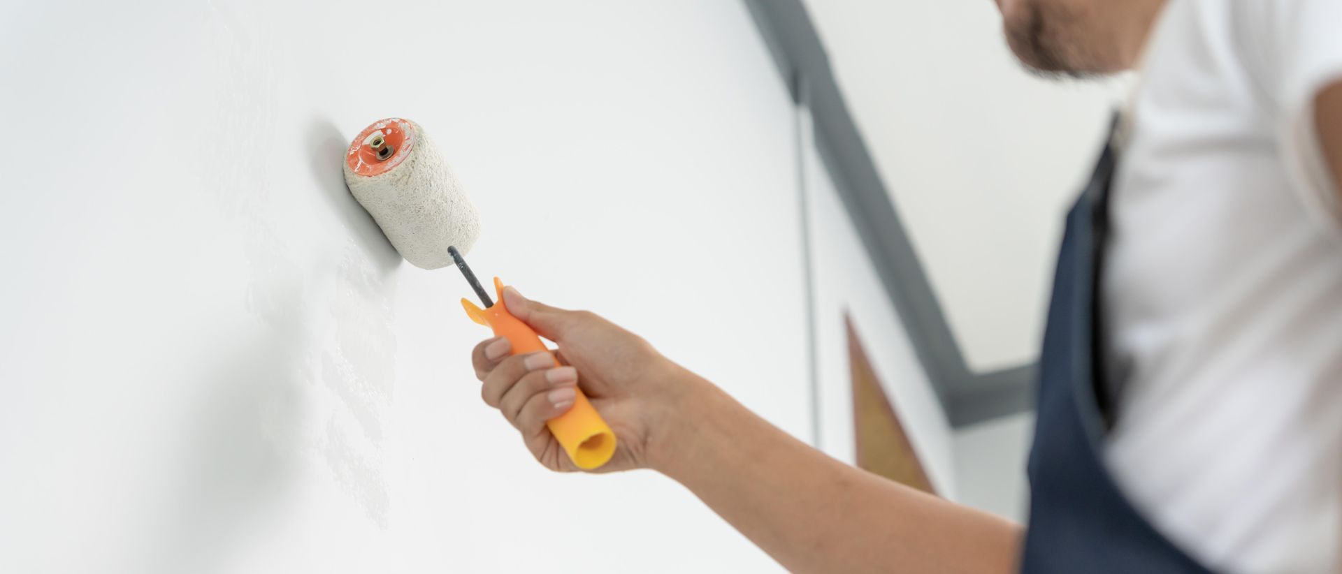 A man is painting a wall with a paint roller.