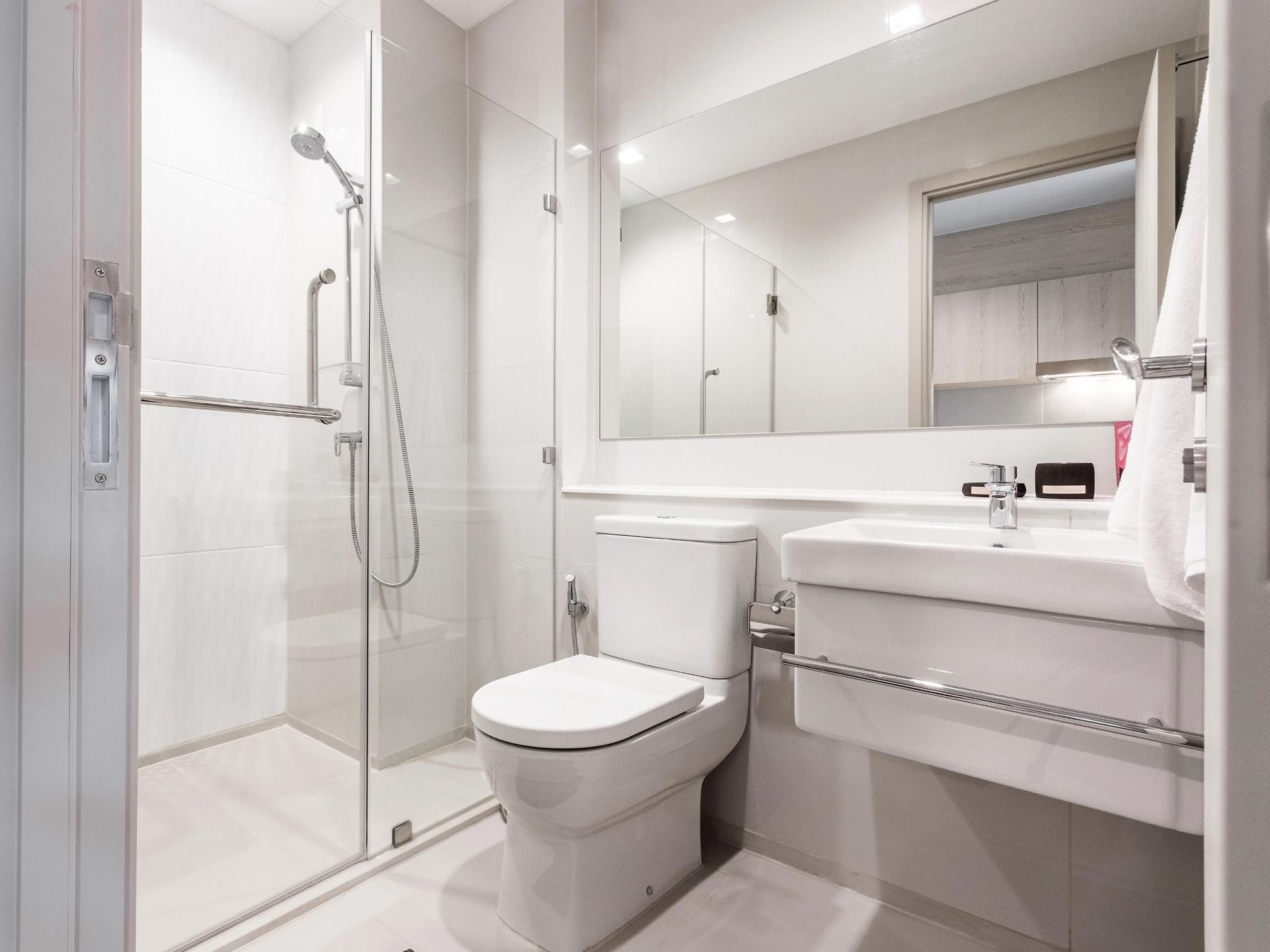 A bathroom with a toilet, sink, shower and mirror.