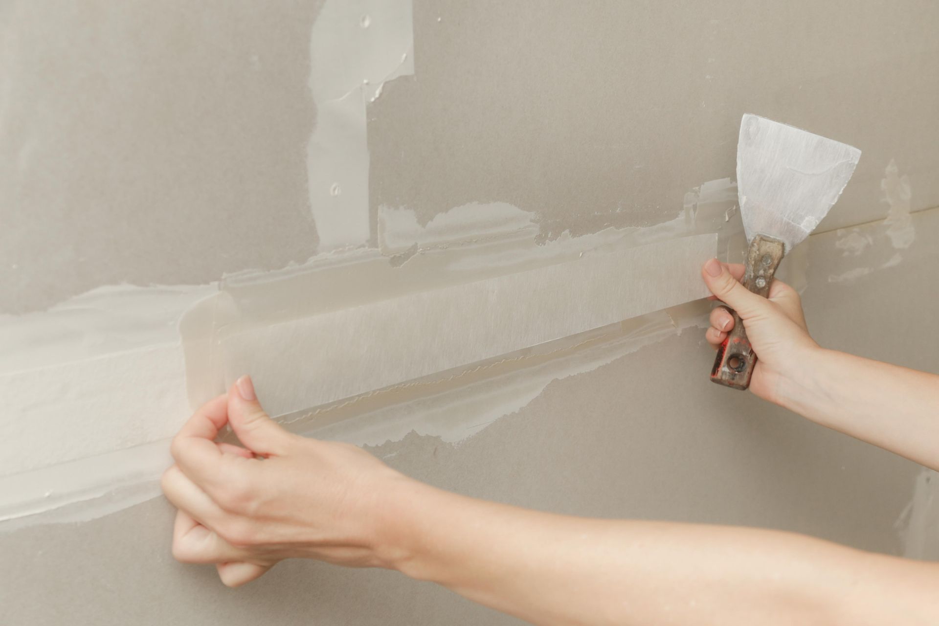 A person is plastering a wall with a spatula.