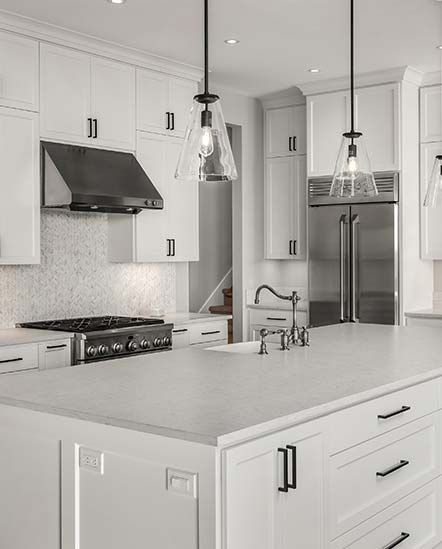 A kitchen with white cabinets, stainless steel appliances, and a large island.