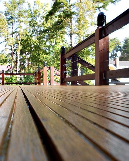 A wooden deck with a fence and trees in the background.