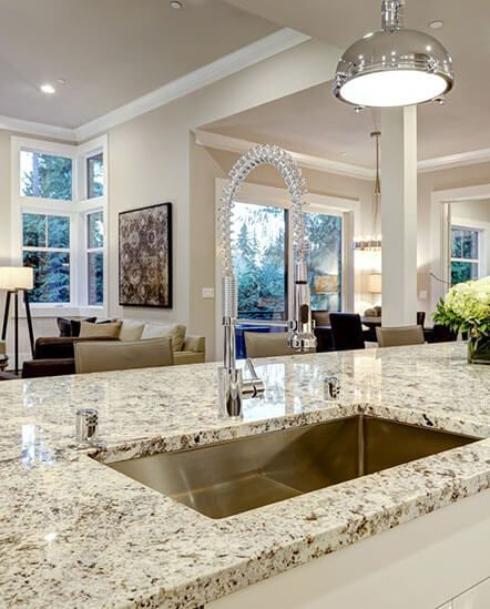 A kitchen with granite counter tops and a stainless steel sink.