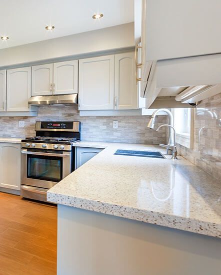 A kitchen with white cabinets, stainless steel appliances, granite counter tops ,and hardwood floors.