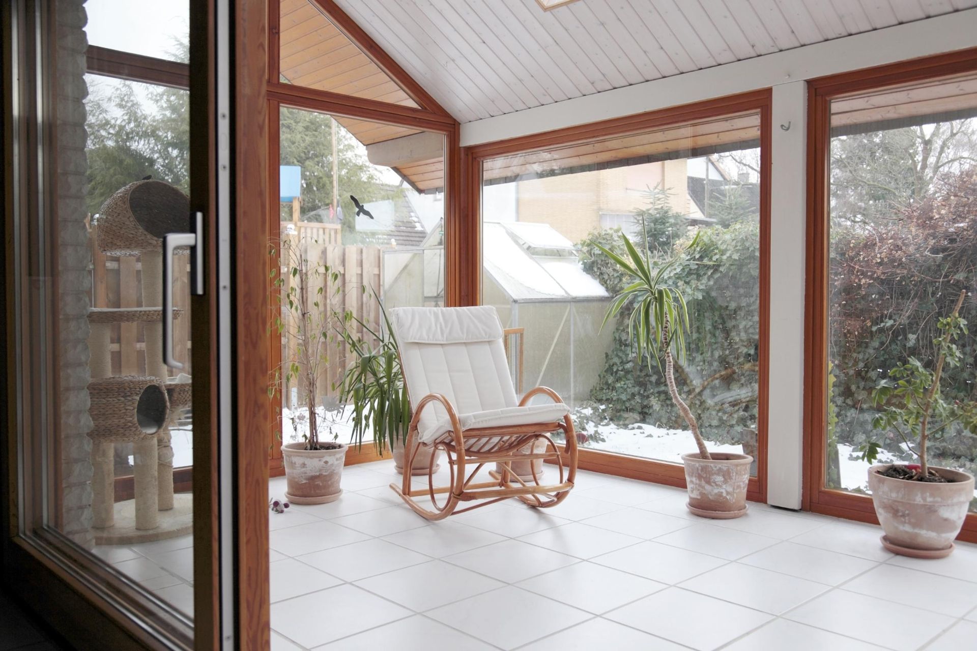 A rocking chair is sitting in a room with a lot of windows.