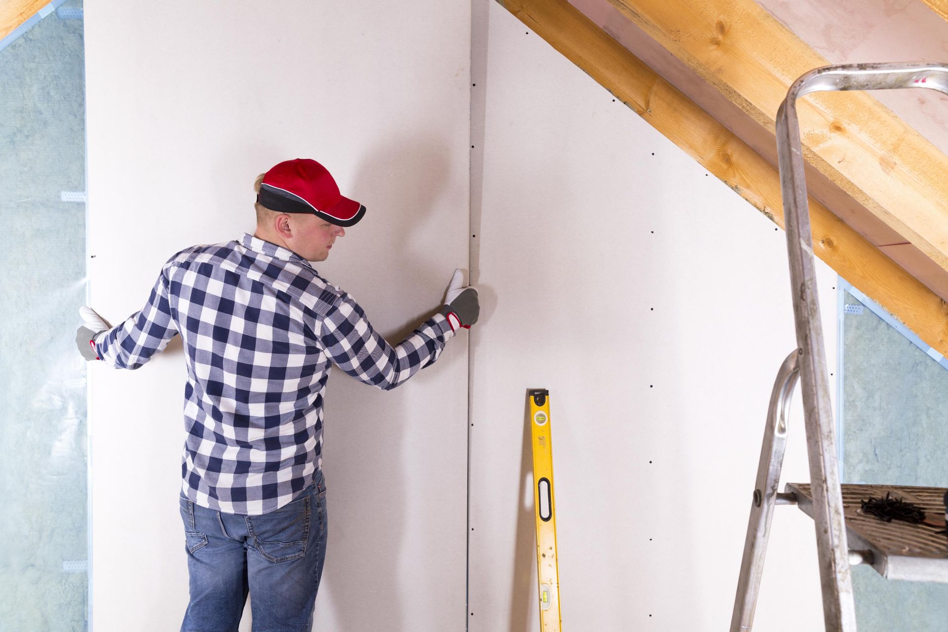 A man is measuring a wall with a level.