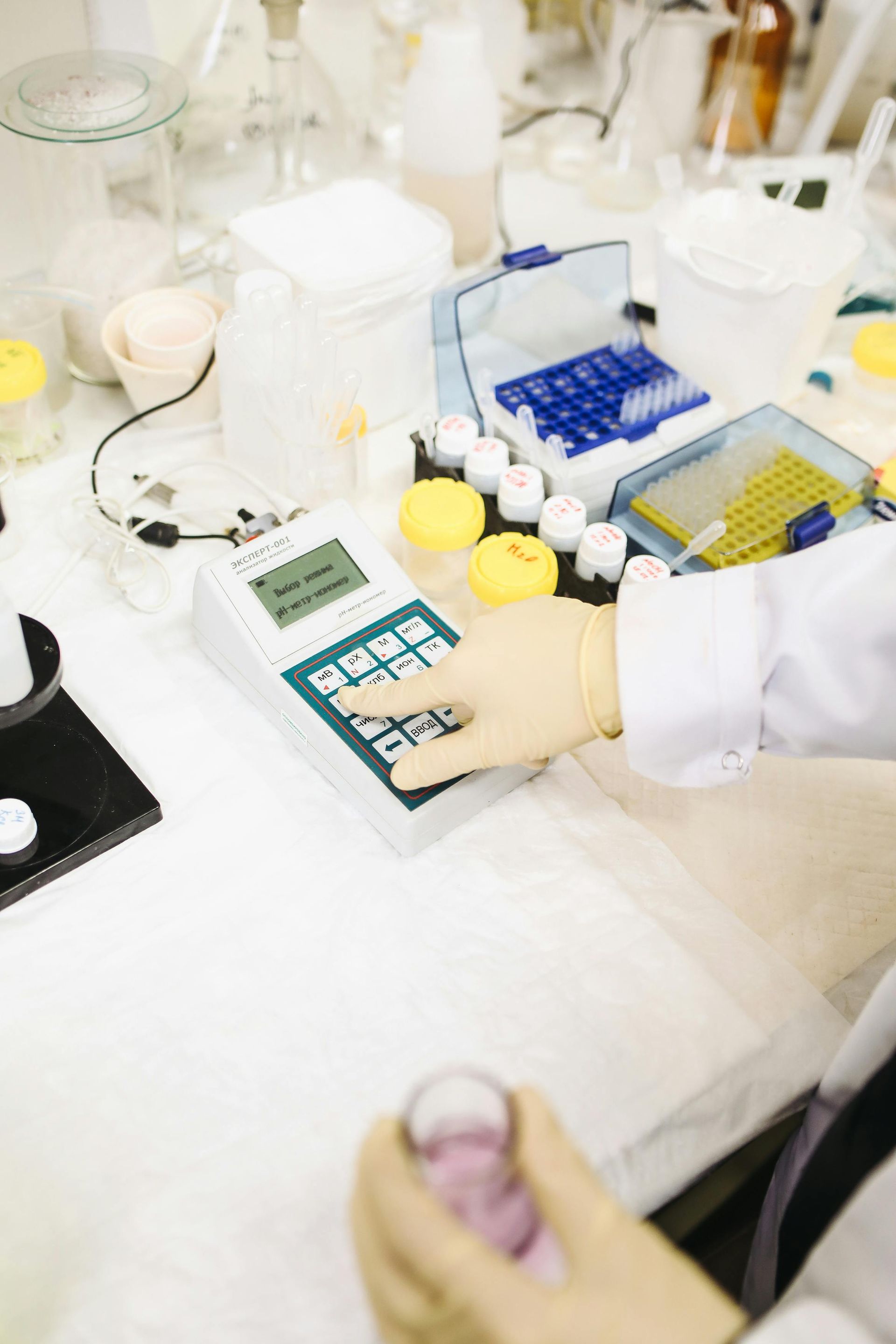 A person is using a calculator in a lab while holding a test tube.