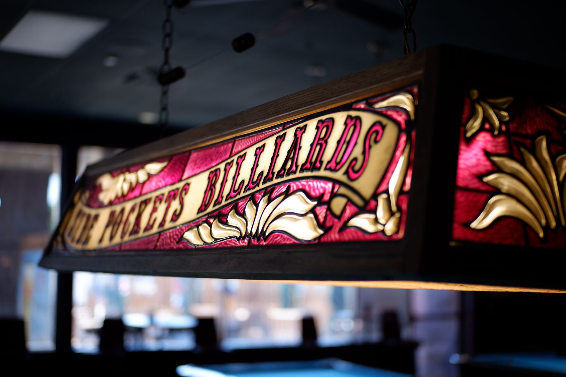 A pool table light hanging from the ceiling at Side Pockets Wichita that says Side Pockets billiards