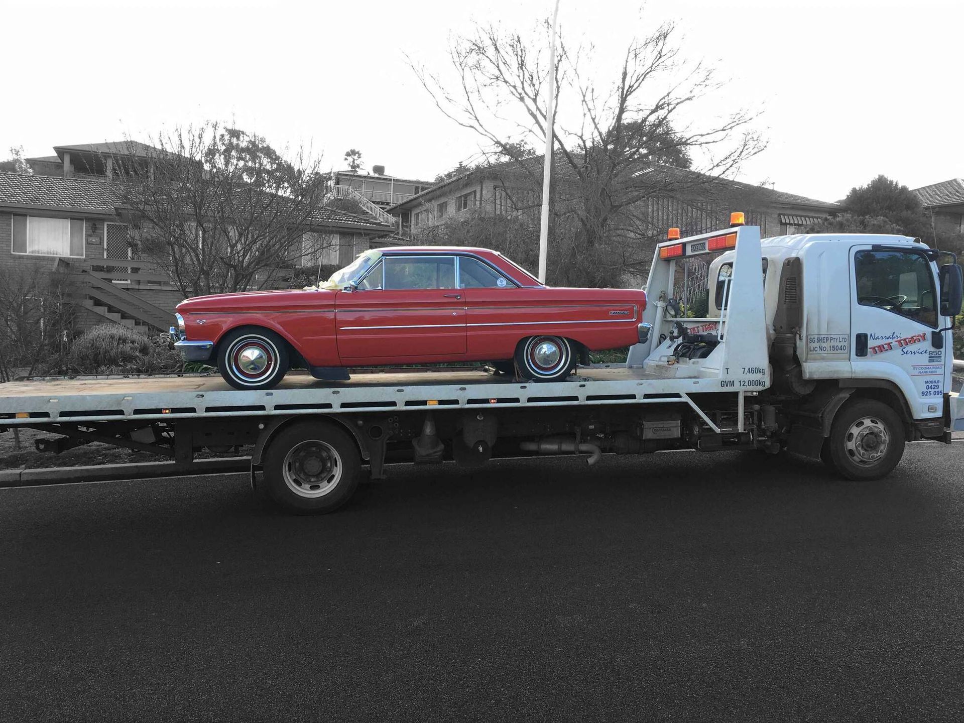 A red car is being towed by a tow truck.