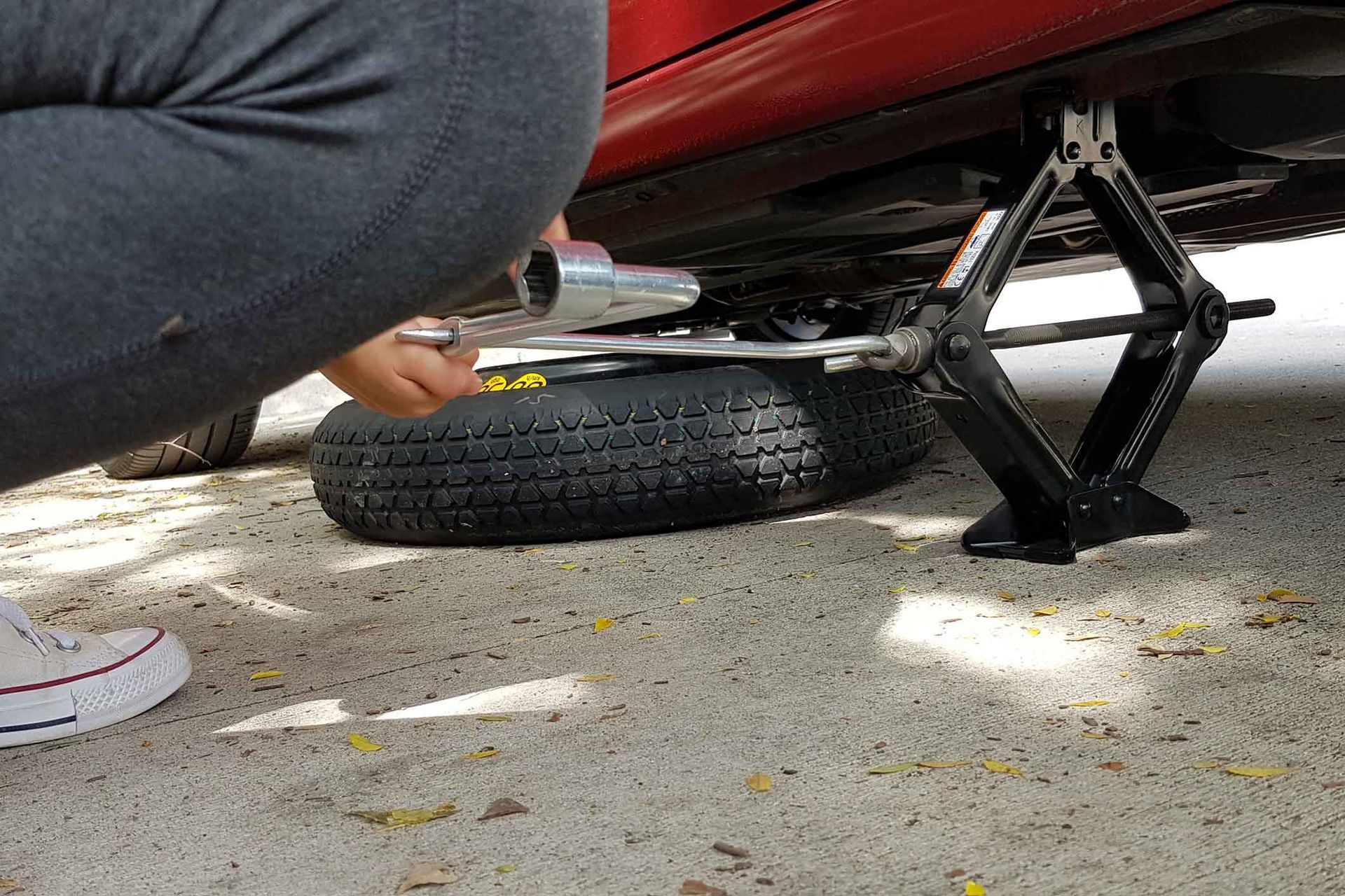 A person is changing a tire on a car with a jack.