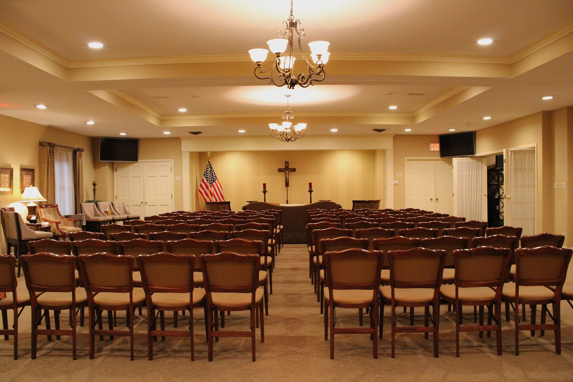 A large room with rows of chairs and a cross on the wall