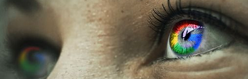 Close-up of a person's eye with the Google logo reflected in the iris, with multiple colors.