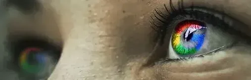 Close-up of a person's eye with the Google logo reflected in the iris, with multiple colors.