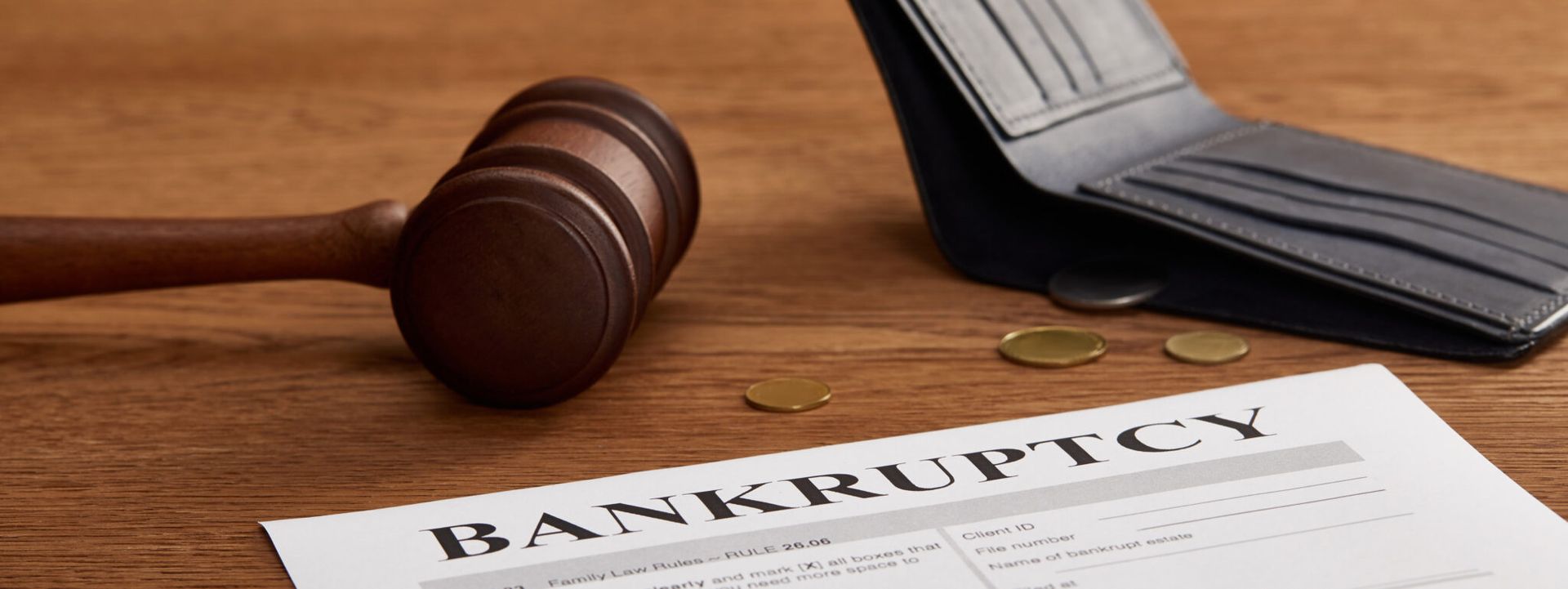 A judge 's gavel is sitting on top of a bankruptcy paper next to a wallet and coins.