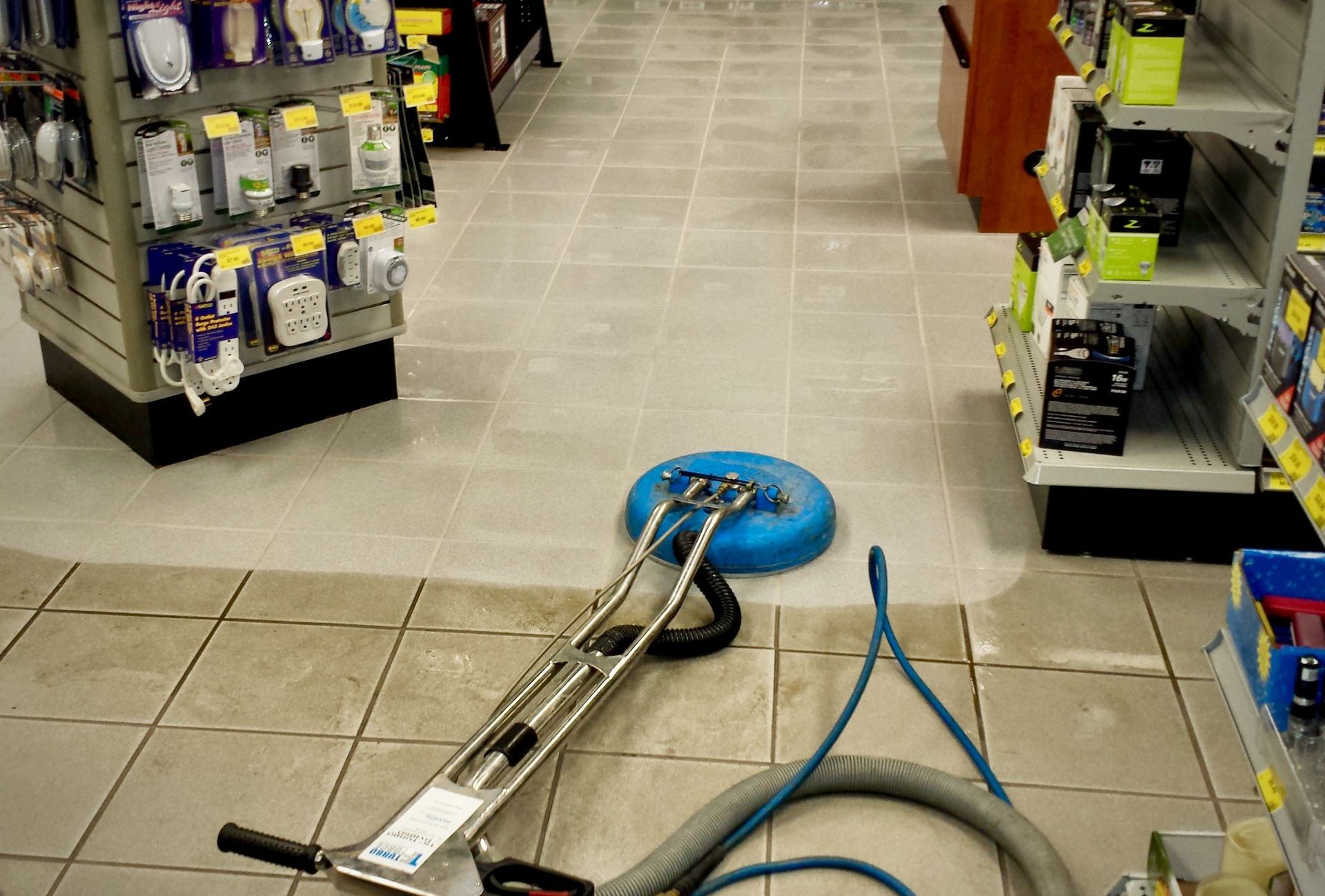 A vacuum cleaner is sitting on a tiled floor in a store.