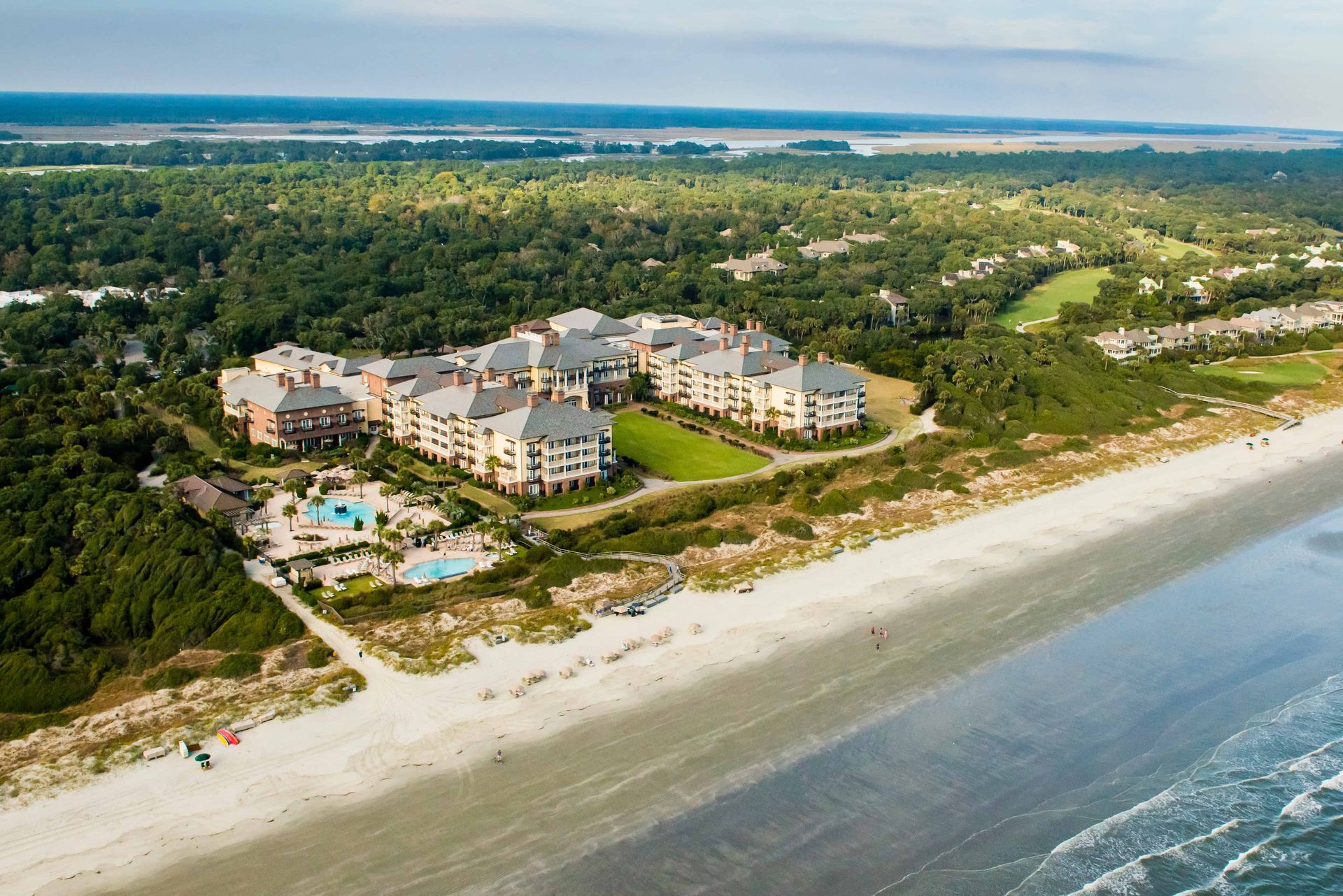 An aerial view of a beach with a hotel in the background