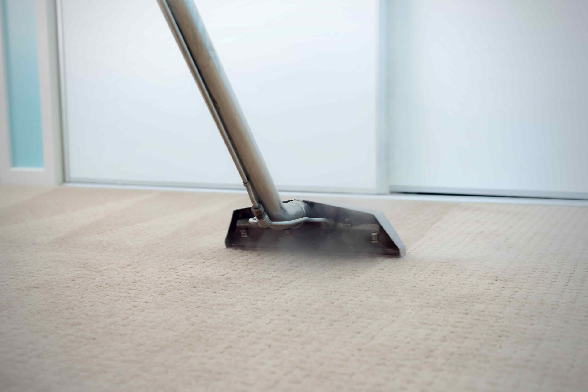 A vacuum cleaner is cleaning a carpet in a room.