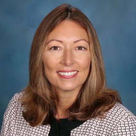 A woman is smiling for the camera in front of a blue background.