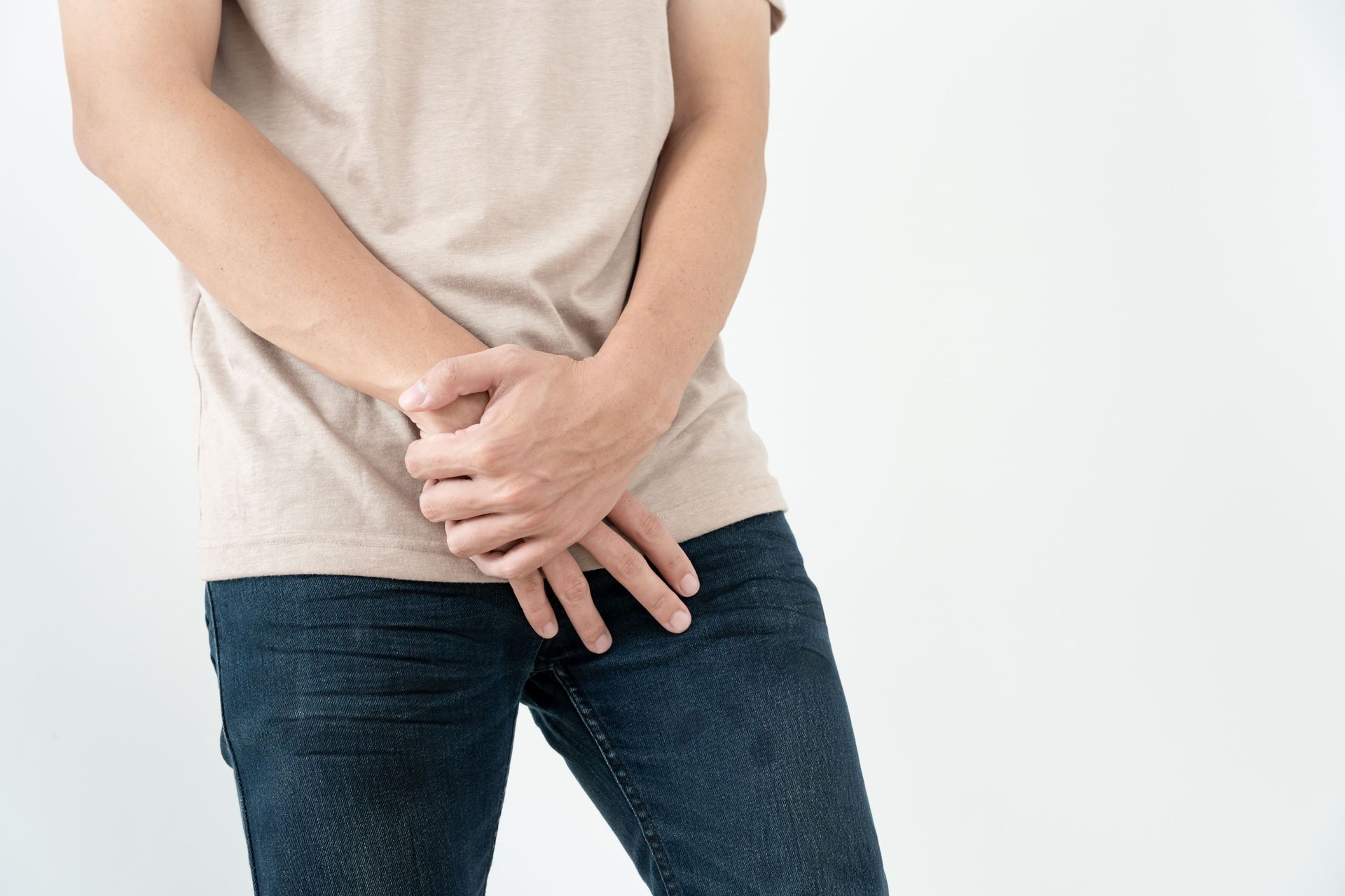 A man is holding his hands to his lower abdomen.