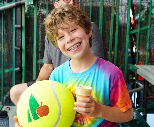 Smiling boy with large tennis ball and ice cream