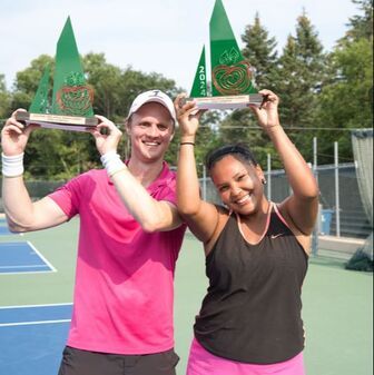 Players lift trophy at Pine Tree Apple Tennis Classic.