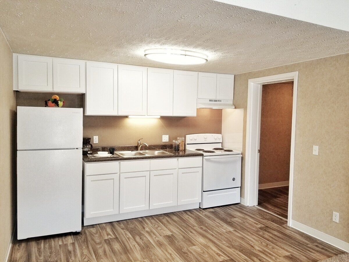 A kitchen with white cabinets , a refrigerator , a stove , and a sink.