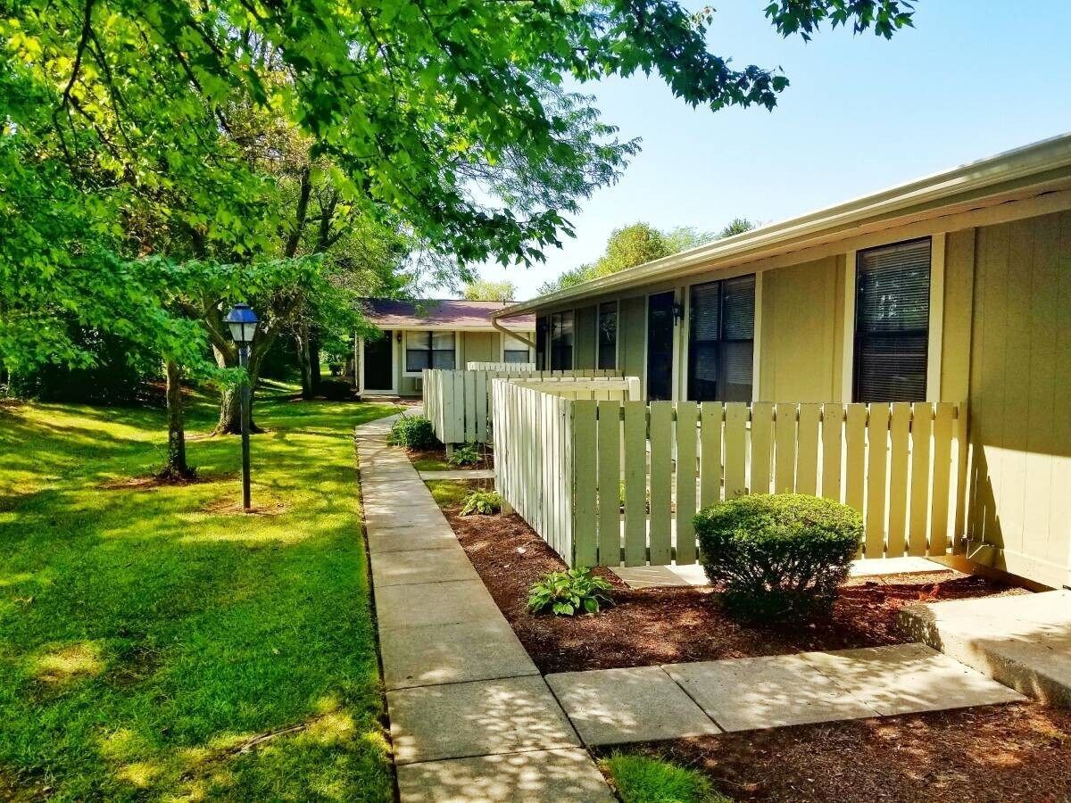 A house with a white picket fence and a walkway leading to it.