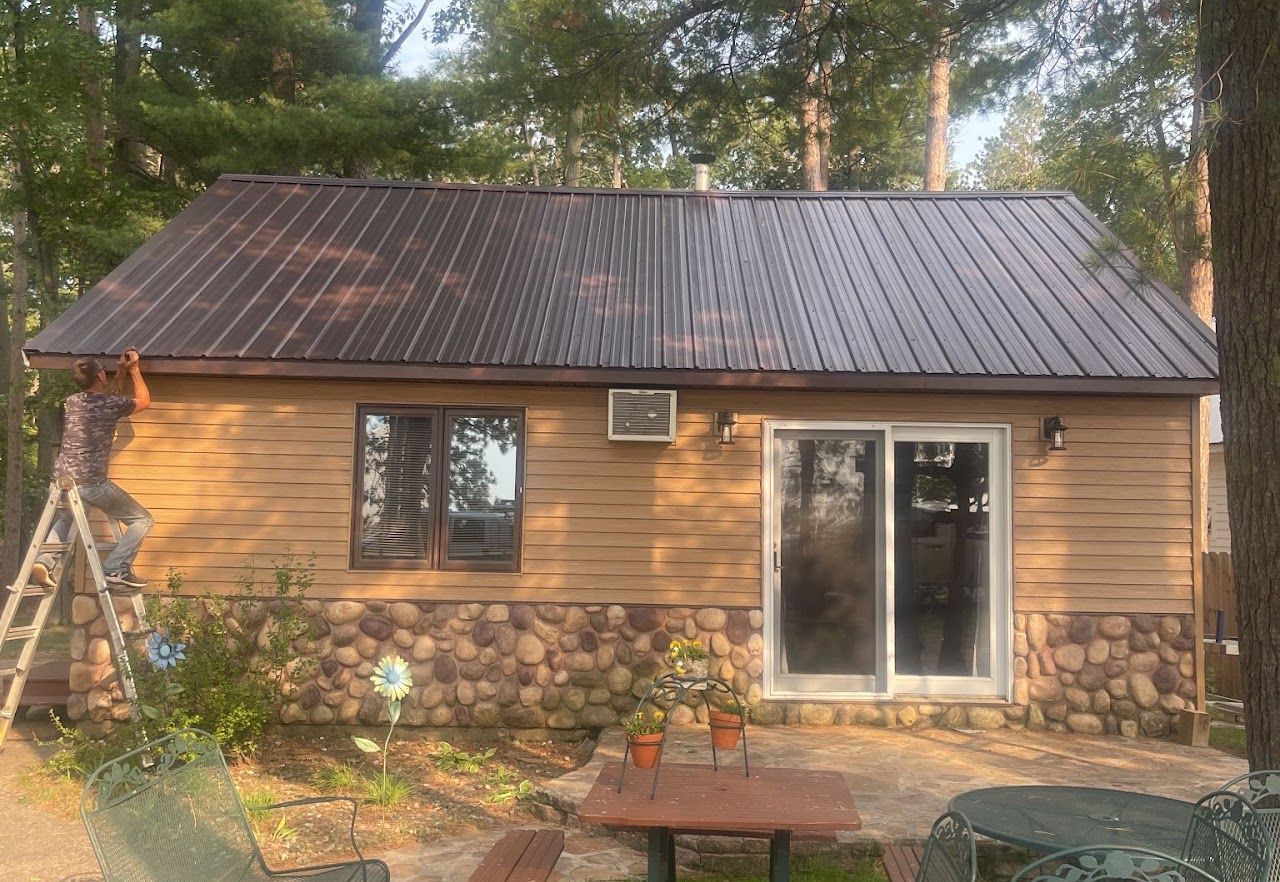 A small house with a metal roof and a picnic table in front of it.