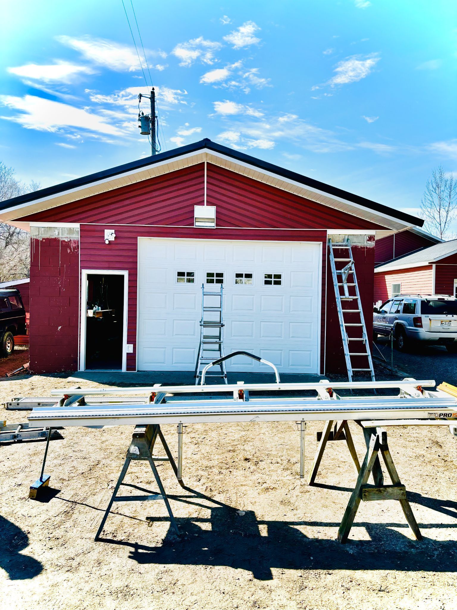 A red garage with a white garage door and a ladder in front of it
