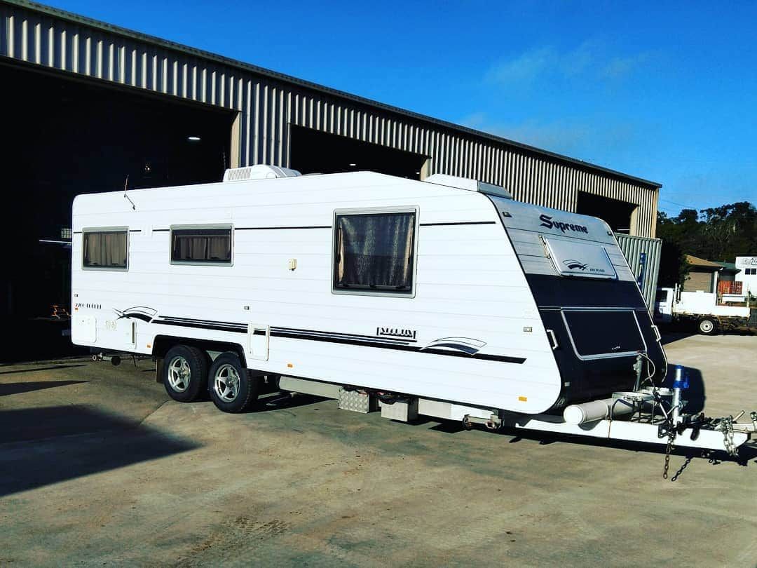 White Caravan Parked on a Concrete Surface in Front of a Large Building — Boycey's Custom Engineering in Atherton, QLD