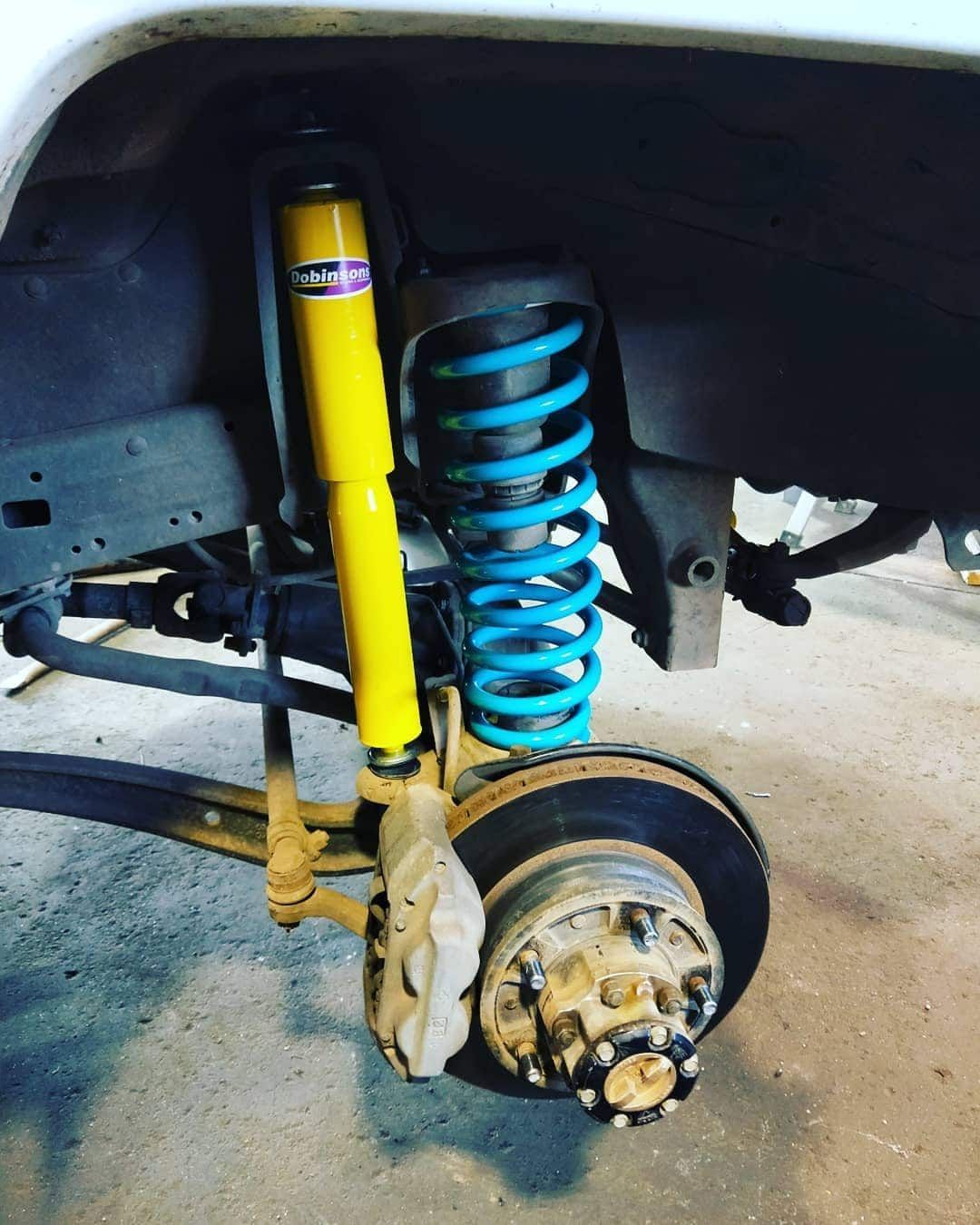 Yellow Shock Absorber and Blue Coil Spring on a Vehicle's Suspension — Boycey's Custom Engineering in Atherton, QLD