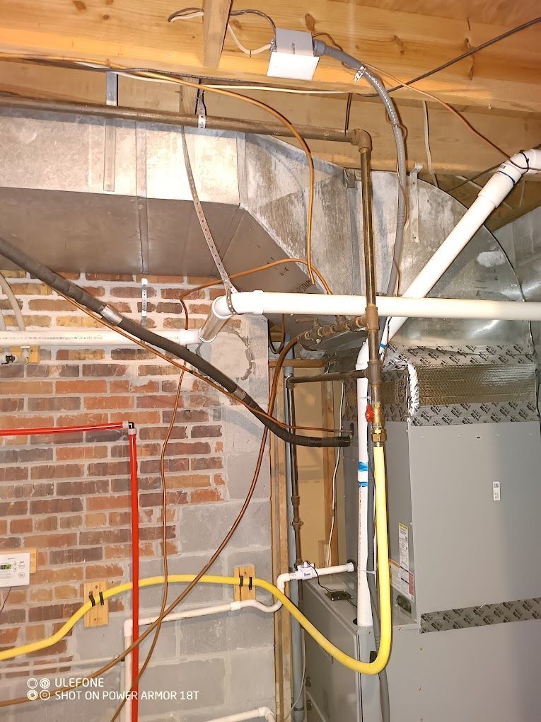 A picture of a basement with a furnace and pipes hanging from the ceiling.