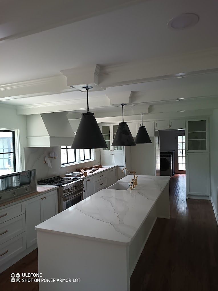 A kitchen with white cabinets and a large island in the middle.