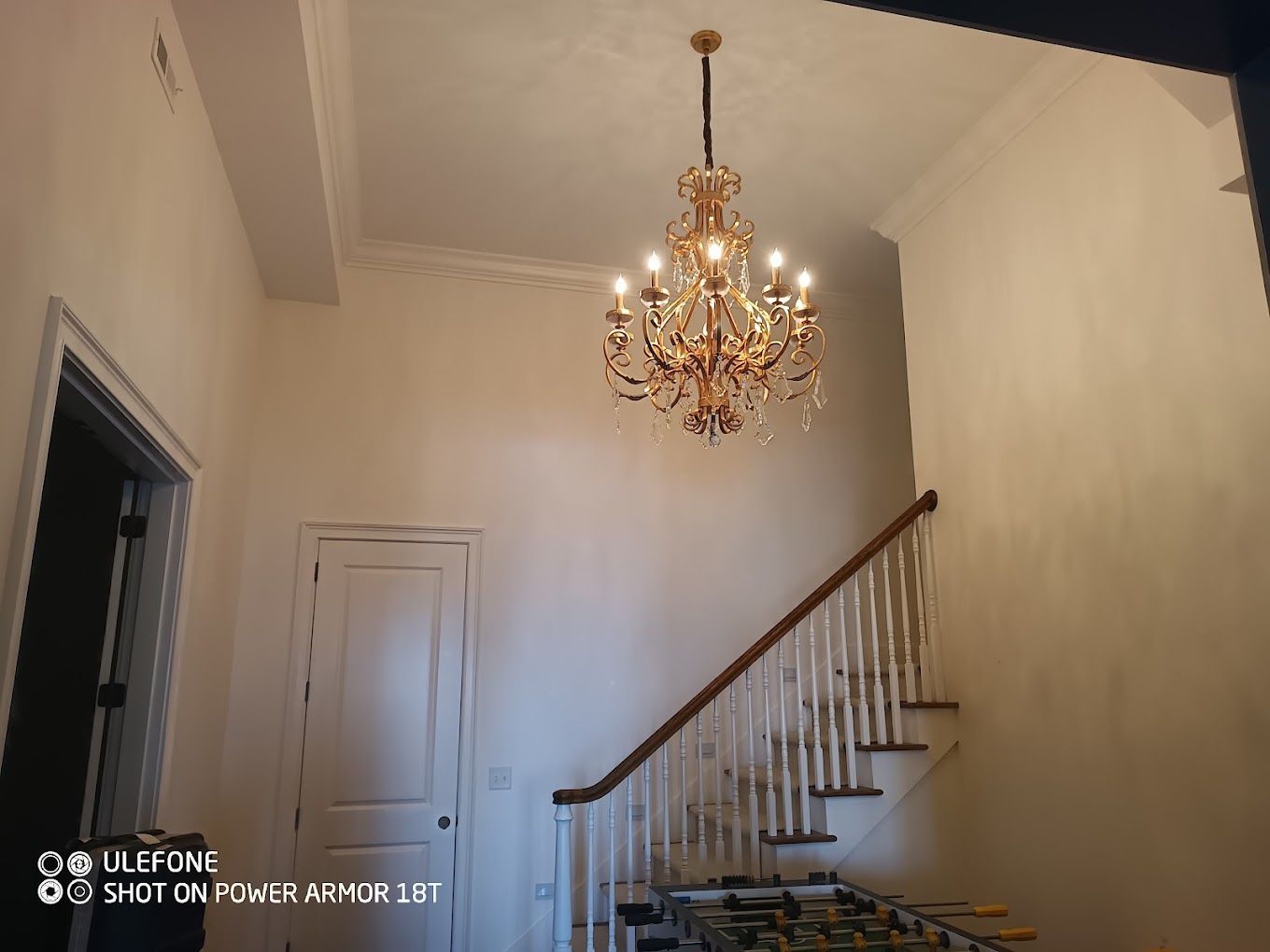 A chandelier is hanging from the ceiling above a staircase.
