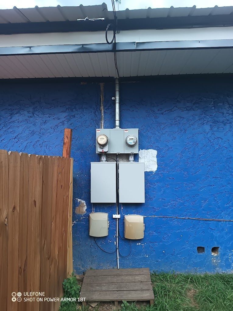 A blue wall with electrical boxes on it and a wooden fence.
